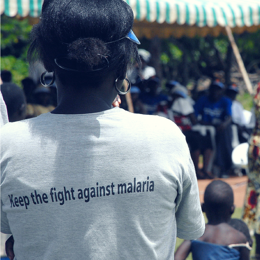 African lady in village wearing t-shirt saying 'Fight against Malaria'